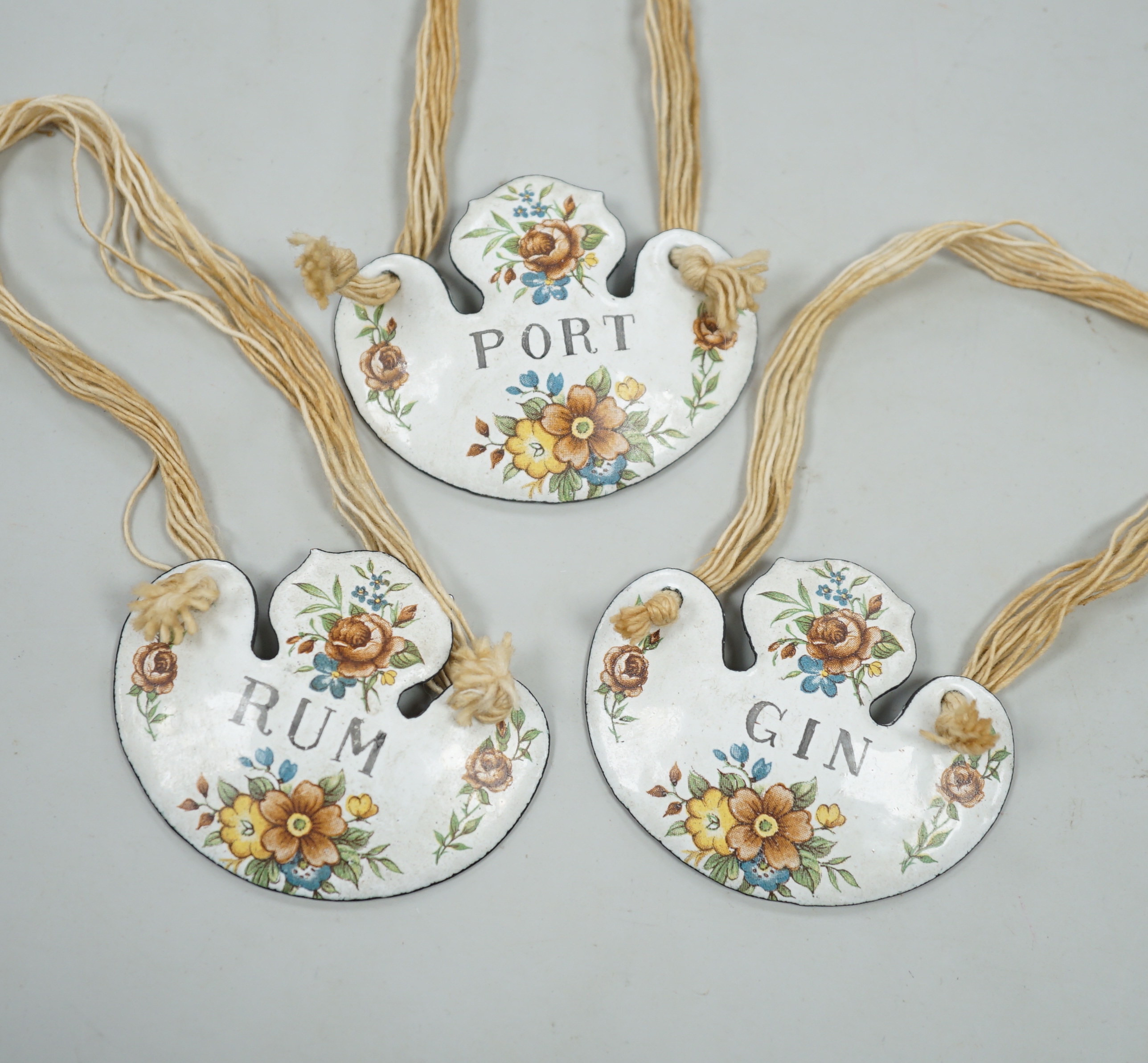 A group of three enamelled bottle labels - ‘rum’, ‘gin’ and ‘port’